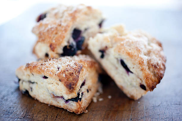 Scones A fresh batch of blueberry scones on a rustic cutting board.  Shot with shallow focus. scone photos stock pictures, royalty-free photos & images