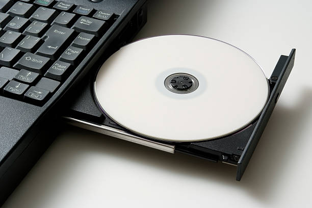 Close-up of laptop with opened and loaded blank DVD drive isolated on white background with shadow.