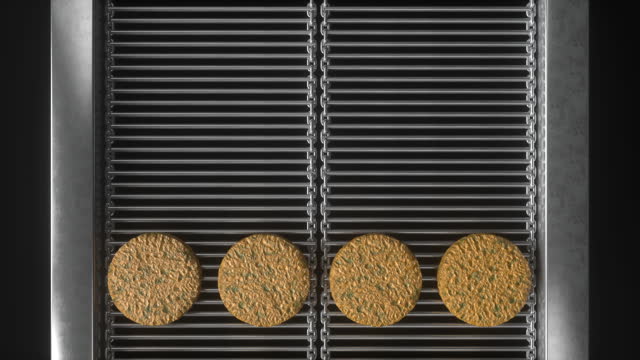 Veggie burgers top view running on a conveyor belt grill machine, automatic broiler