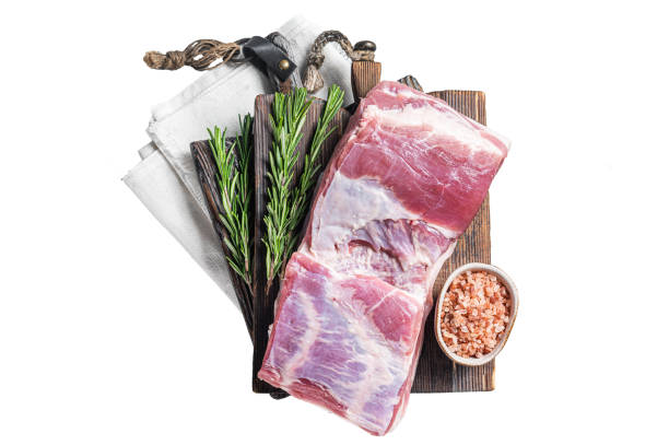 Pork belly block, raw meat with skin on a wooden board with rosemary.  Isolated, white background. Pork belly block, raw meat with skin on a wooden board with rosemary.  Isolated, white background berkshire pig stock pictures, royalty-free photos & images