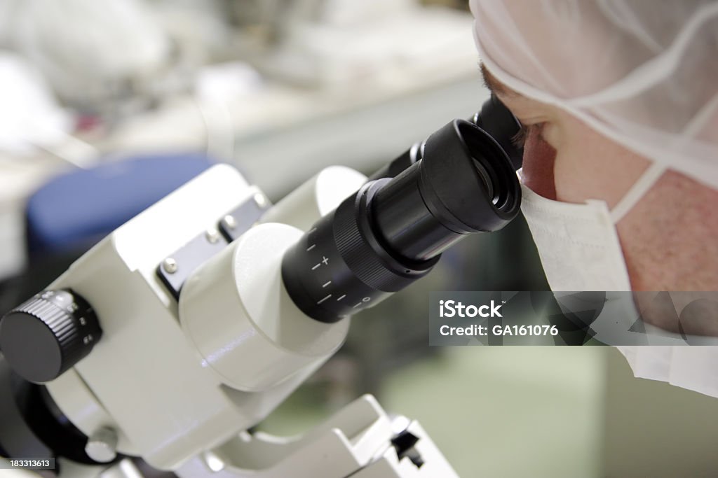 Scienziato Guarda nel microscopio - Foto stock royalty-free di Abbigliamento