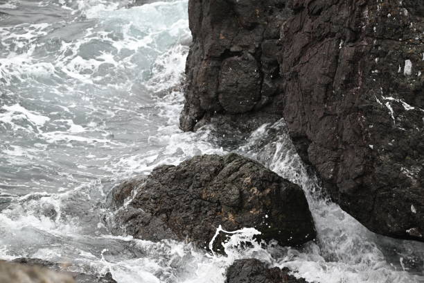 A close-up overlooking view of the tide crashing into a rocky cliffside on San Juan Island, Washington.
