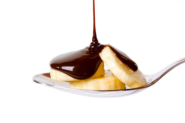 Sliced bananas with chocolate sauce on spoon isolated on white