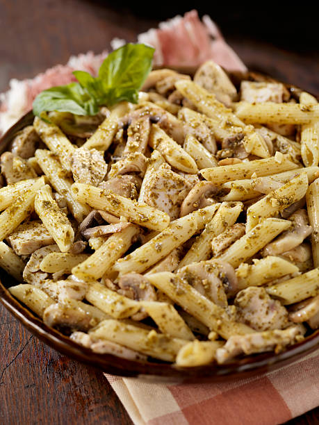 Creamy Pesto Chicken, Mushroom and Penne Casserole "Creamy Pesto Chicken, Mushroom and Penne Casserole -Photographed on Hasselblad H3D-39mb Camera" cooked selective focus vertical pasta stock pictures, royalty-free photos & images