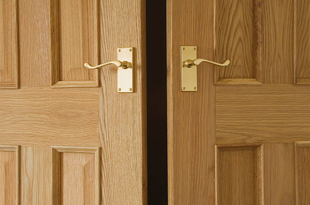 Open doors "Close up of slightly open wooden doors, with brass door handles." ajar stock pictures, royalty-free photos & images