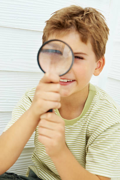 istock Little boy looking through magnifying glass 183315752