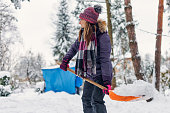 Teenage girl making a path in snow in backyard