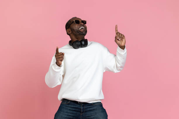 istock Smiling black man wearing white sweatshirt pointing up at copy space 1833171704