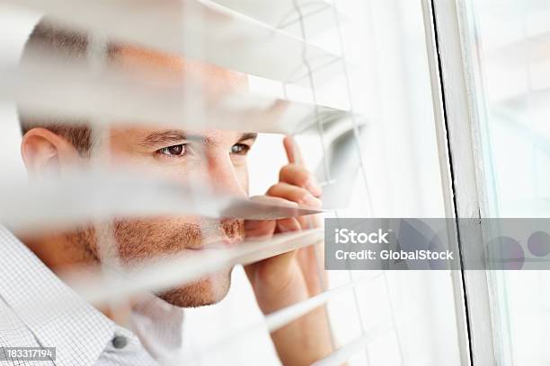 Young Man Peeking Out Of The Window Blinds Stock Photo - Download Image Now - 20-29 Years, 30-39 Years, Adult