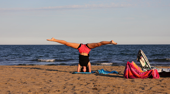 young girl performs leg splits during training on the beach and sunset