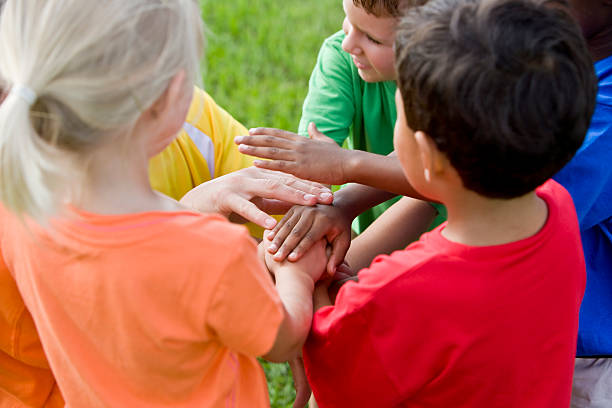 группа детей младшего возраста, руки в центре с взаимодействие - preschooler plant multi ethnic group preschool стоковые фото и изображения