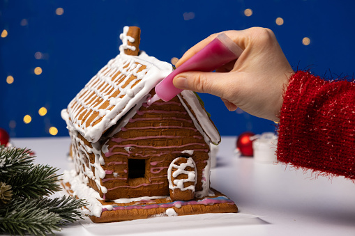 The process of decorating a ginger Christmas house with sugar icing.