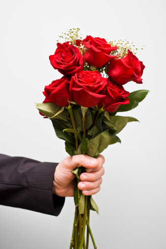 Man stands with a bouquet of red roses in his hand