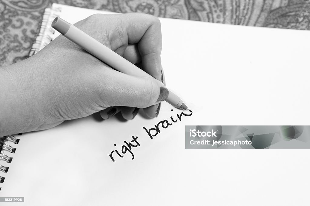 Left Handed Uses Right Brain Left hand writing right brain on paper. Black and white presentation. Left Handed Stock Photo