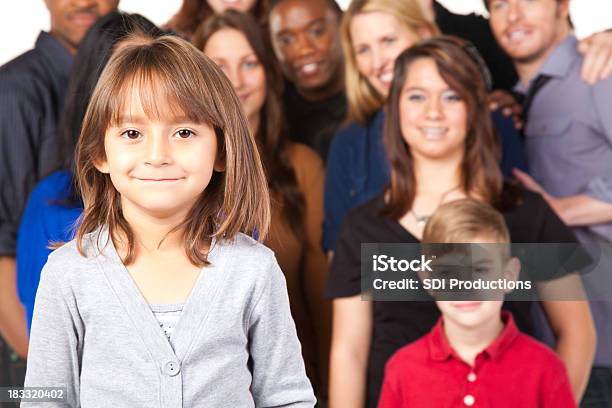 Foto de Menina Sorridente Com Grupo De Pessoas Olhando No Seu e mais fotos de stock de Adulto