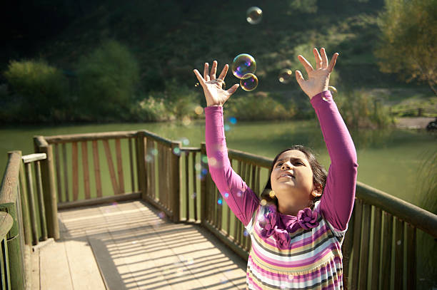 Little girl is playing with bubbles.