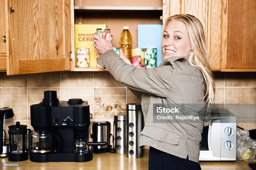 Linda rubia en la cocina, para alcanzar en armario de compra de comestibles - Foto de stock de Armario libre de derechos