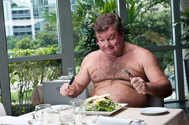 Hungry Shirtless overweight mature caucasian man having a salad in a restaurant fat guy no shirt stock pictures, royalty-free photos & images
