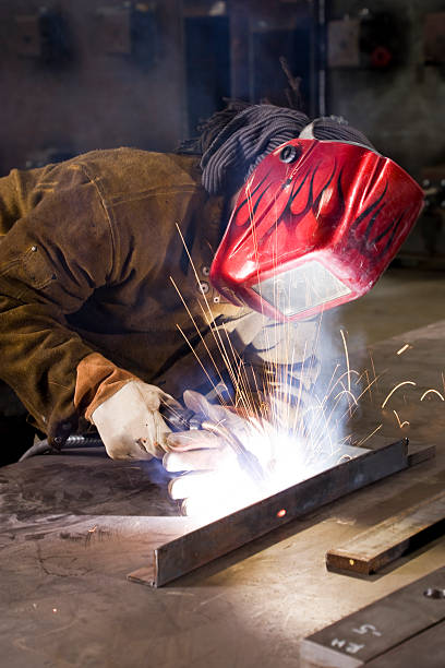 A welder in a special mask performs welding work.