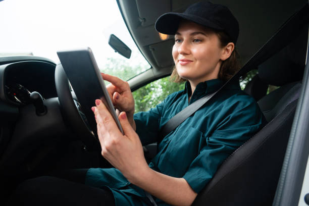 istock Woman courier sitting in a car and looking at a digital tablet. 1833219020