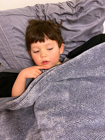 View of a little boy sleeping in bed