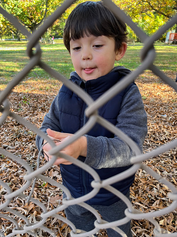 View of a little boy standing behind fence