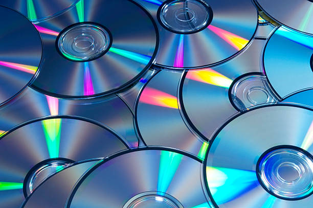 Blue tinted image of stacked CD/DVD texture background High angle view and blue tinted image of CD/DVD texture background. compact disc stock pictures, royalty-free photos & images