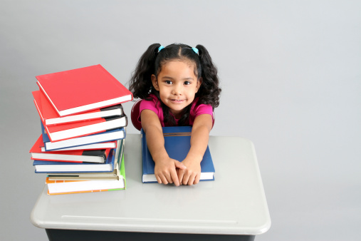 Adorable Hispanic preschool girl sitting at a desk with textbooks and an eager look on her face. Click photo below to view my other education and learning images.