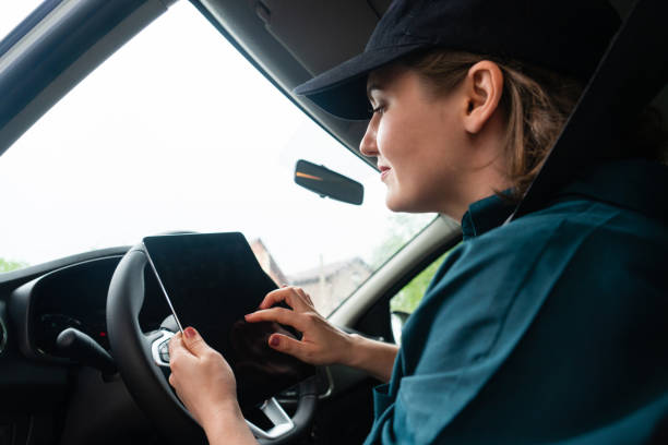 istock Woman courier sitting in a car and looking at a digital tablet. 1833234592