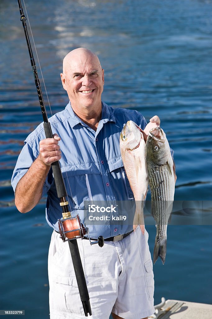 Senior fisherman with rod and fresh catch Senior man in his 60s, with striped bass and red snapper caught deep sea fishing 60-64 Years Stock Photo