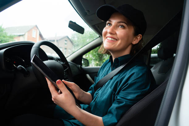 istock Woman courier sitting in a car and holding digital tablet. 1833253529