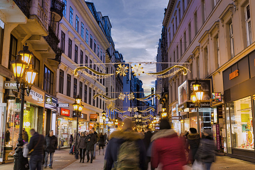 Crowd of people walking on Vaci Street during the Christmas holidays in Budapest at dusk.