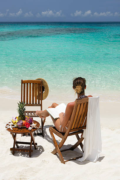 istock bikini woman reading a book at the Caribbean beach 183325566