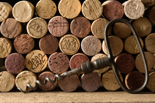 Stack of corks and old corkscrew on a wooden surface.