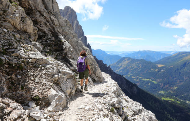 istock Young woman with backpack on the path in high mountains in ALPS 1833271138