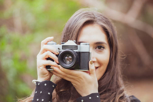 istock Beautiful young woman taking picture outdoors with an analog camera. 1833285862