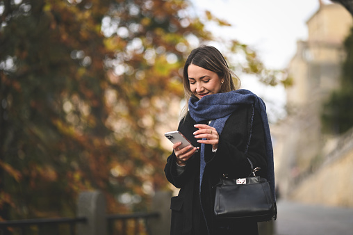 smiling mid adult woman online messaging outdoors.