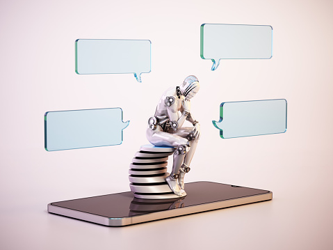 Thinking robot with speech balloons sitting on computer keyboard. AI chatbot concept.