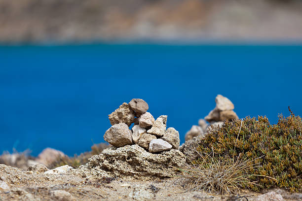 Piled stones and small bush against blue ocean stock photo