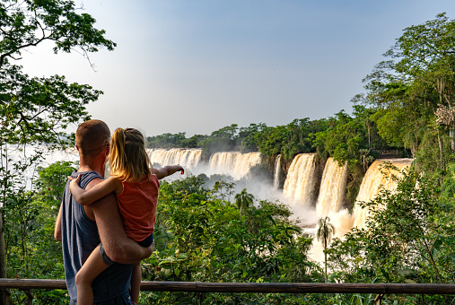 Father and daughter enjoying the breathtaking mighty Iguazu Falls in Iguazu National Park on the Boarder of Argentina and Brazil, South America