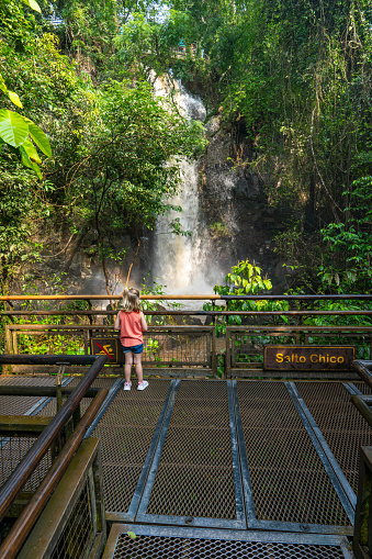 Young Girl Enjoying the breathtaking mighty Iguazu Falls in Iguazu National Park on the Boarder of Argentina and Brazil, South America