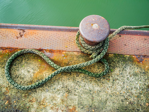Top view of a bollard with laid rope on the harbor shore of Harlesiel in East Frisia Germany.