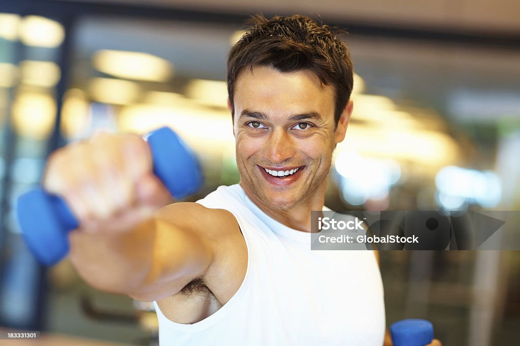 Happy man using dumbbells for his workout Man smiling as he works out with dumbbells 20-29 Years Stock Photo