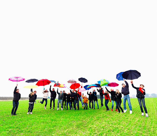 istock Happy young teens jumping while holding umbrellas 183331312