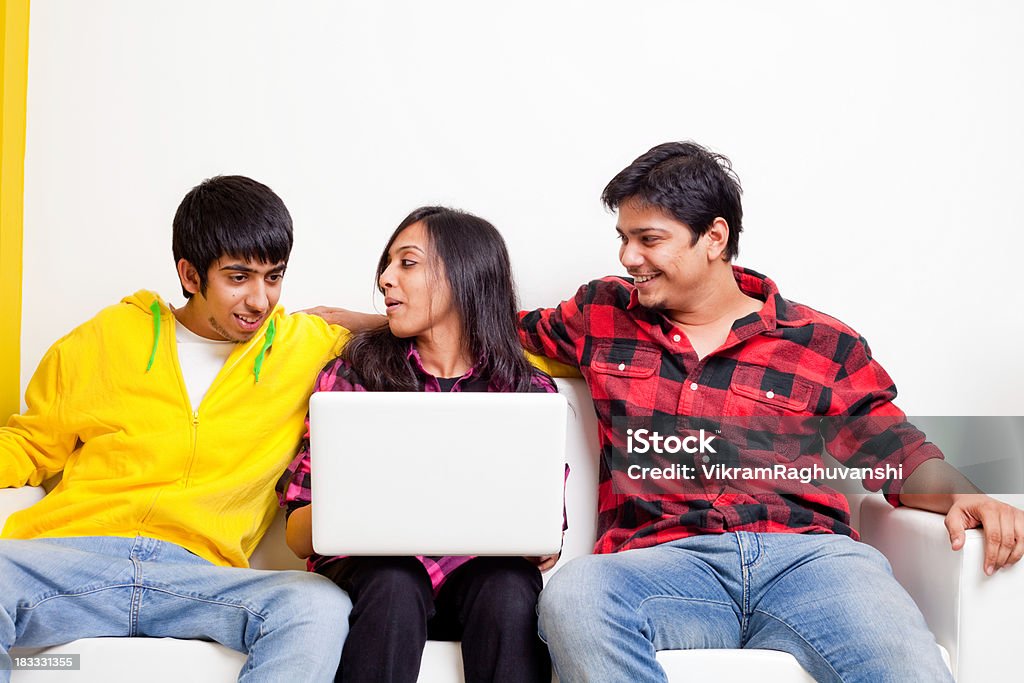 Trois joyeux amis jeunes indienne avec ordinateur portable sur le canapé-lit - Photo de 20-24 ans libre de droits