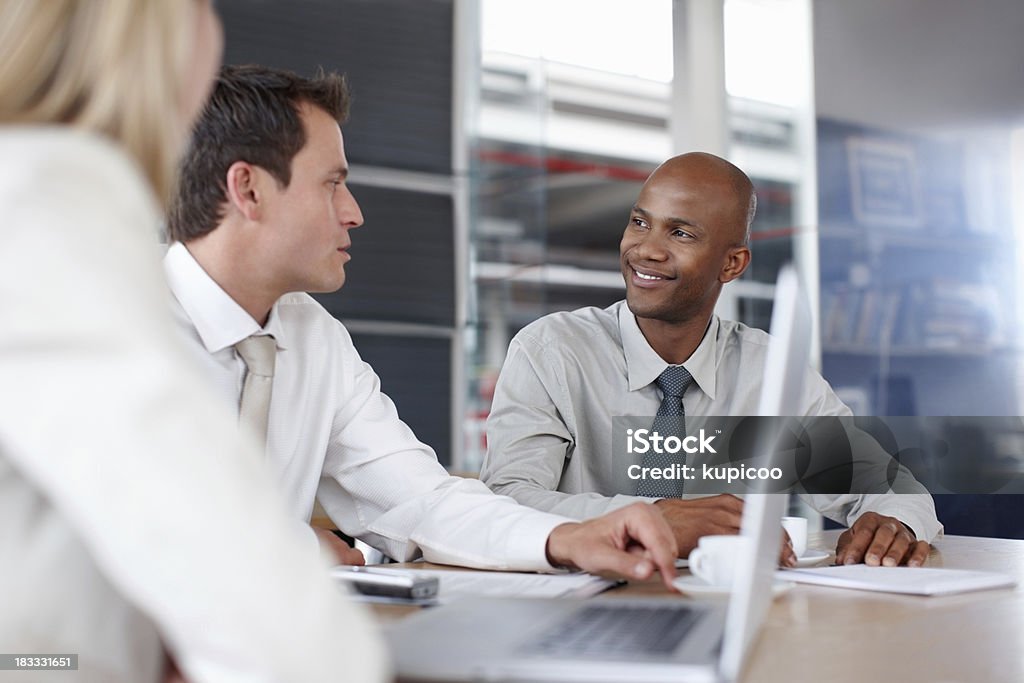 Colleagues in business meeting at office desk African American executive in business meeting with Caucasian colleagues at desk 20-29 Years Stock Photo