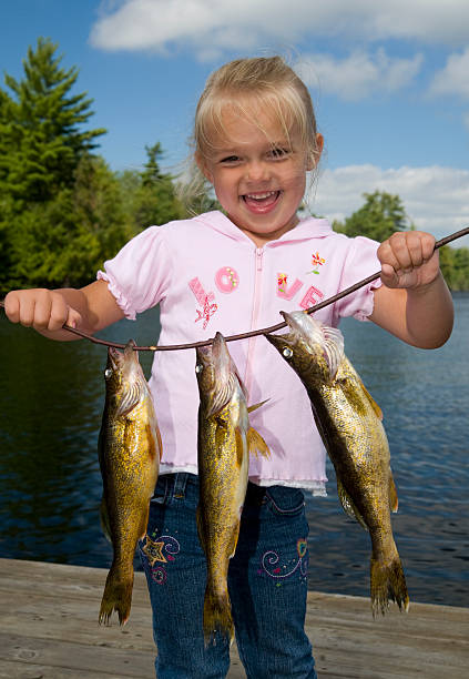 istock Smiling young girl holding a line with three fish 183331790