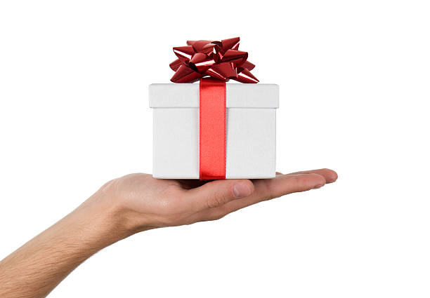 Close-up of hand holding up white gift box with red ribbon man holding gift box with red ribbon against white background hand holding gift stock pictures, royalty-free photos & images