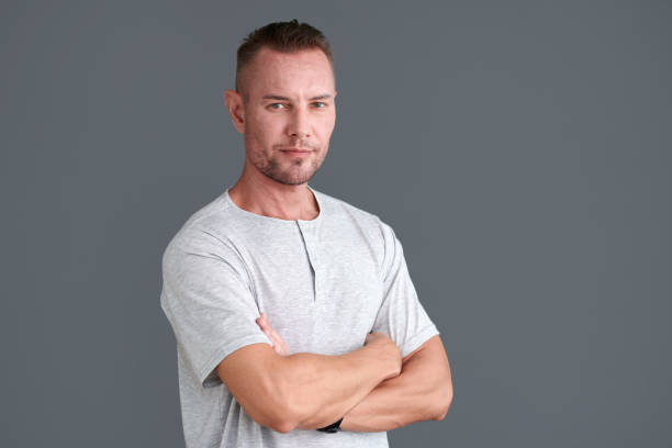 Portrait of confident mature man in grey tshirt crossing arms and looking at camera