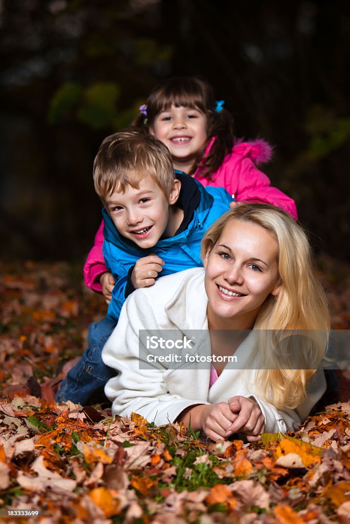 Mãe e duas crianças brincando na floresta no outono - Foto de stock de Adulto royalty-free